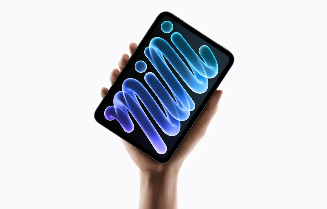 Apple iPad mini held in one hand, with a blue and violet pattern on its screen